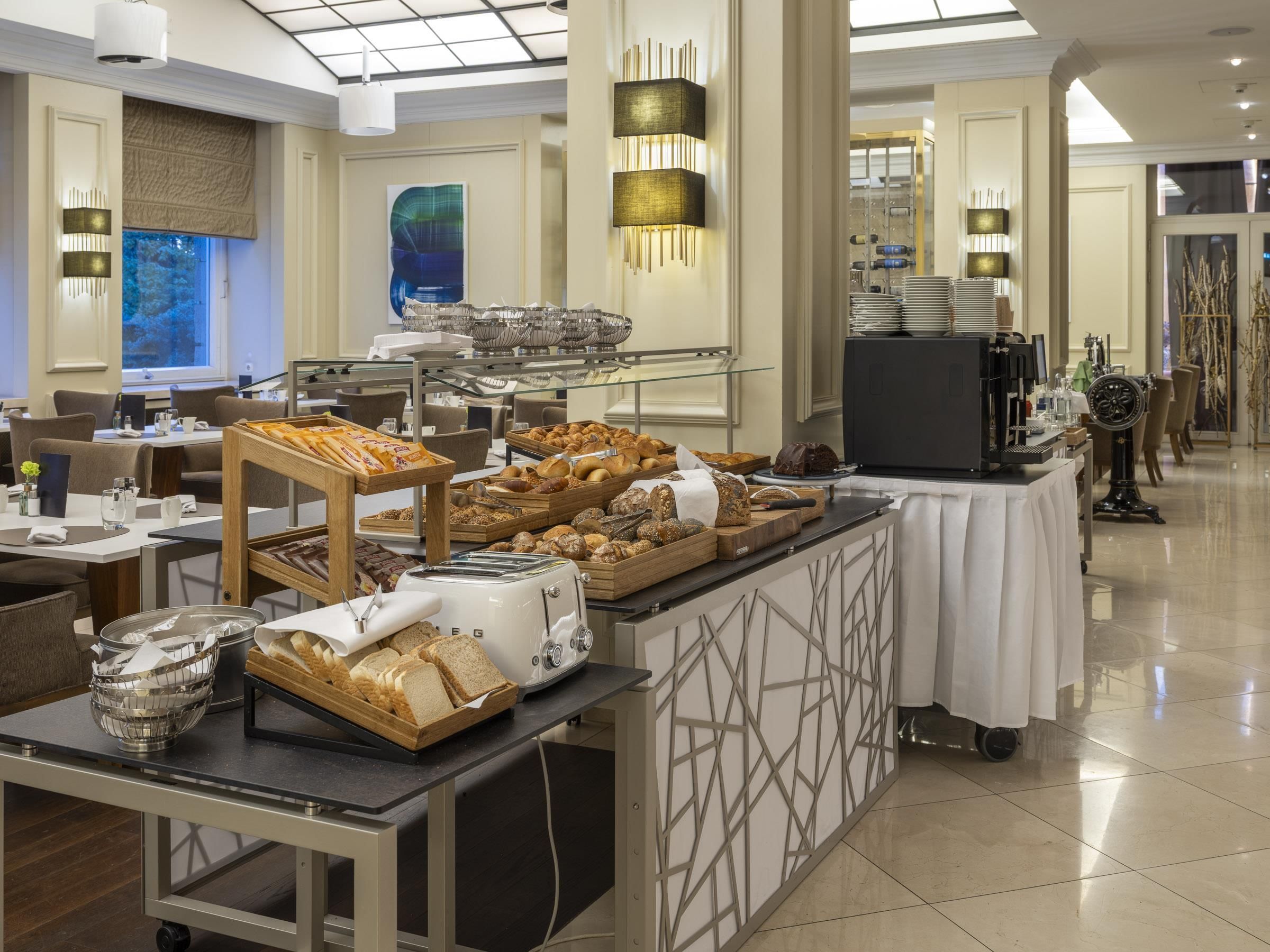 Un área de bufé con diversas opciones de comida, una estación de café y mesas y sillas.