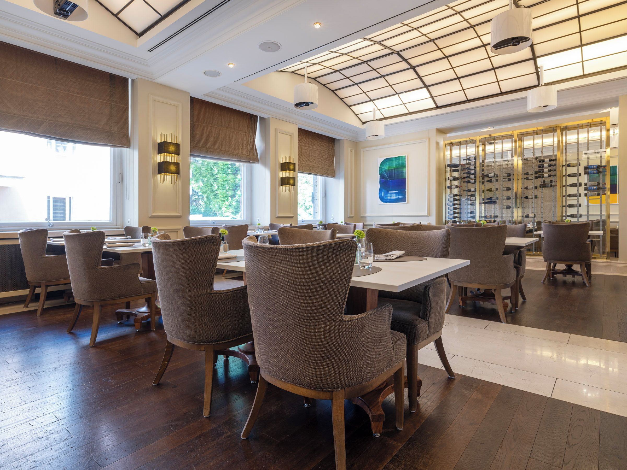 Un interior de restaurante con suelo de madera, mesas redondas y sillas.