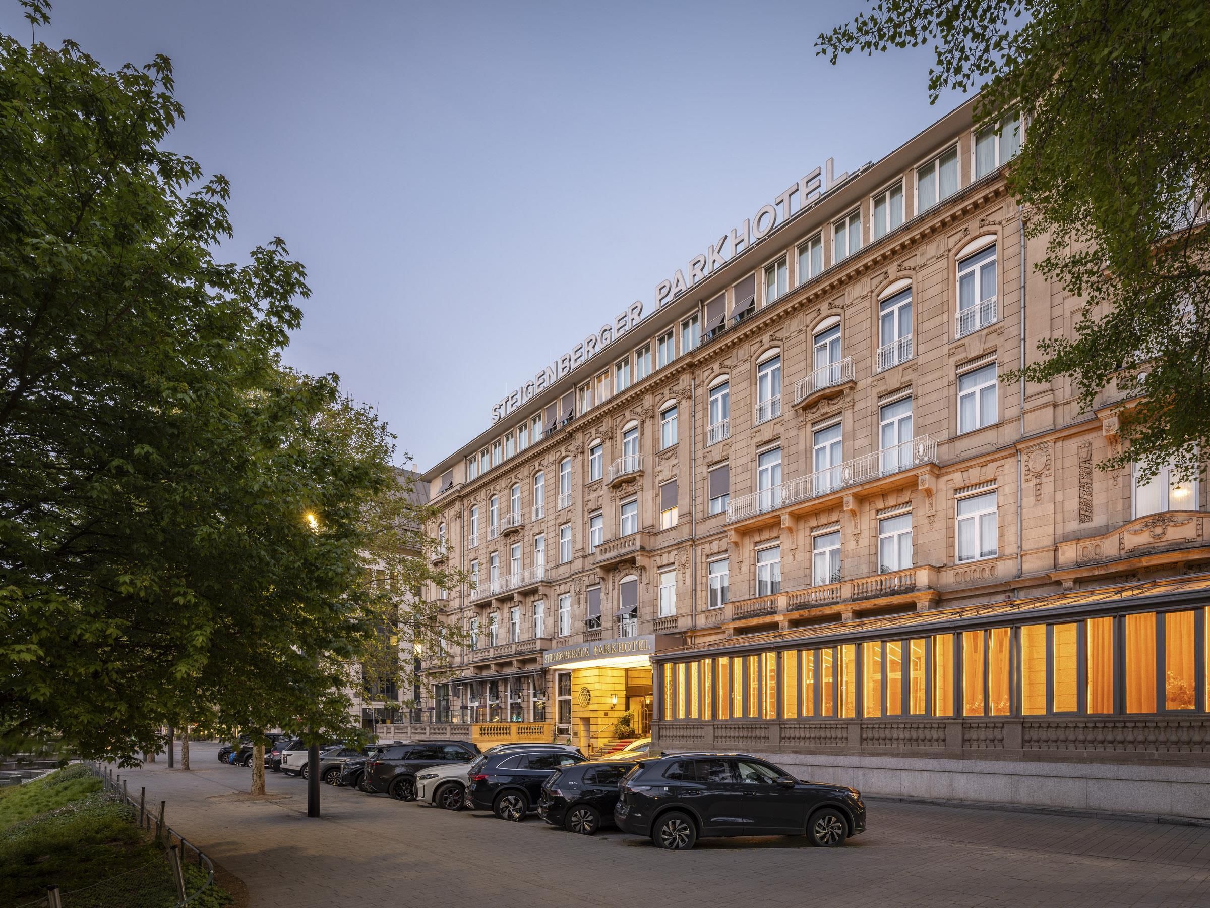 Un hotel de varios pisos con estilo arquitectónico clásico, que cuenta con una entrada destacada con señalización iluminada.