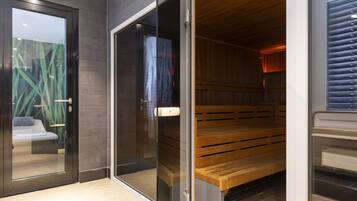 A sauna room with a bench and glass doors.