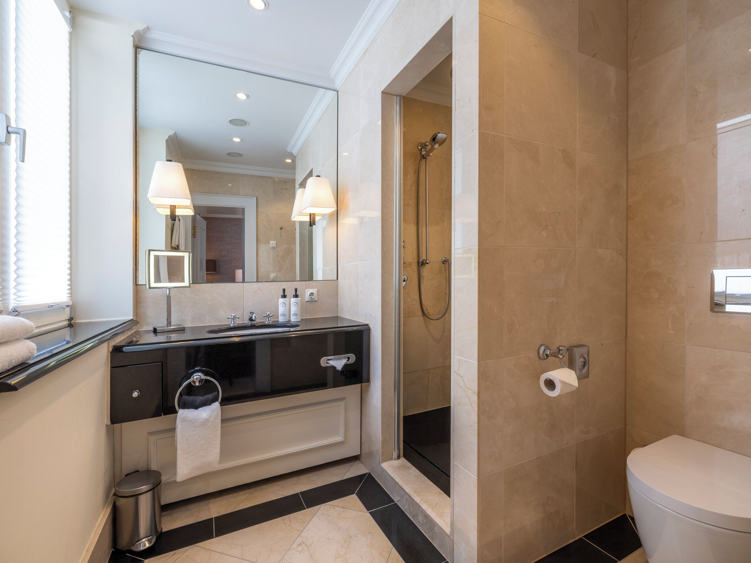 A modern bathroom with a black vanity, a mirror, a shower, and a toilet.