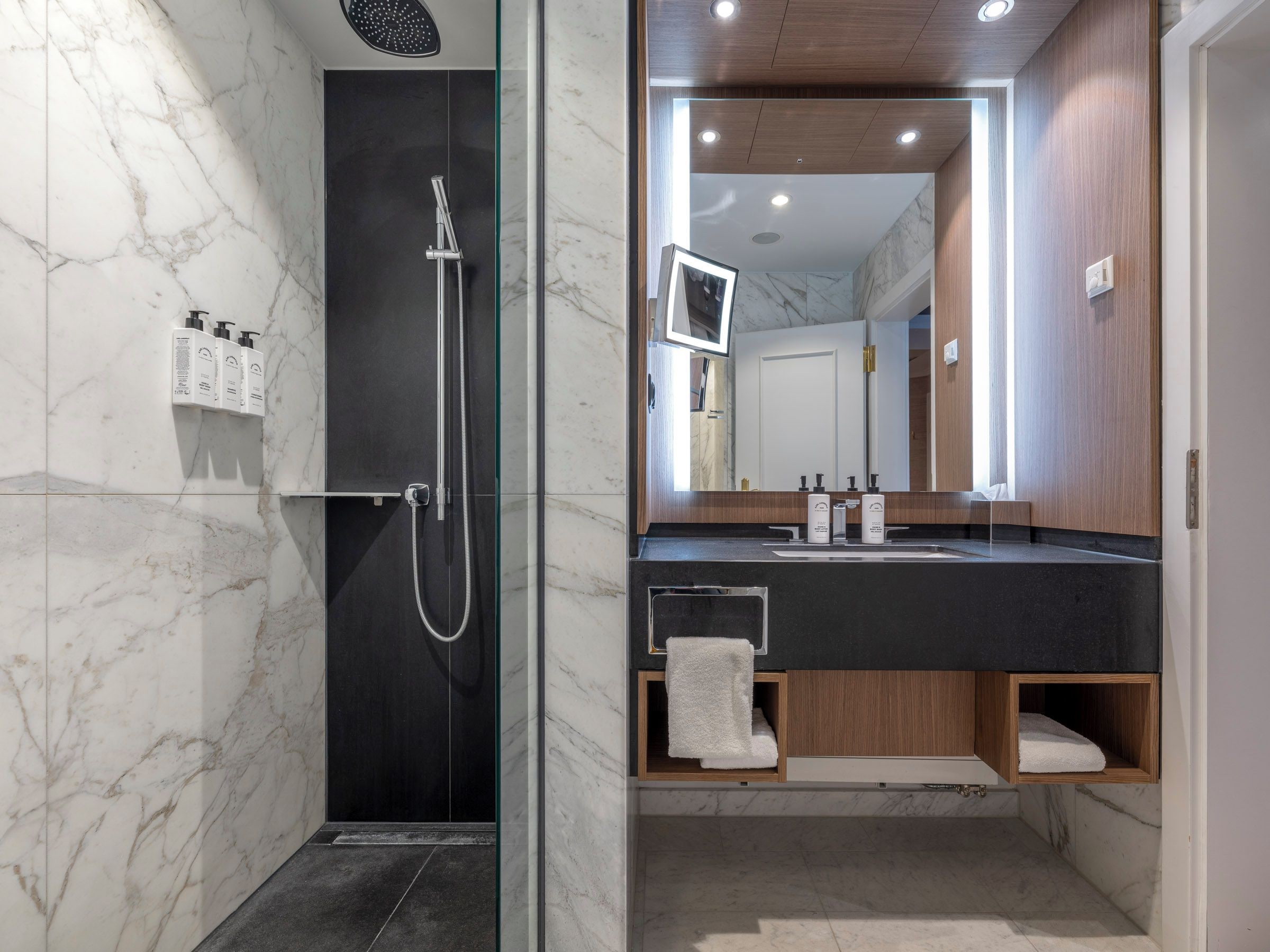 A modern bathroom with a glass-enclosed shower, a vanity with a mirror, and built-in shelves.