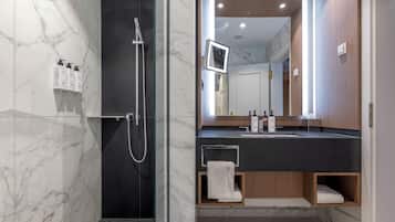 A modern bathroom with a glass-enclosed shower, a vanity with a mirror, and built-in shelves.