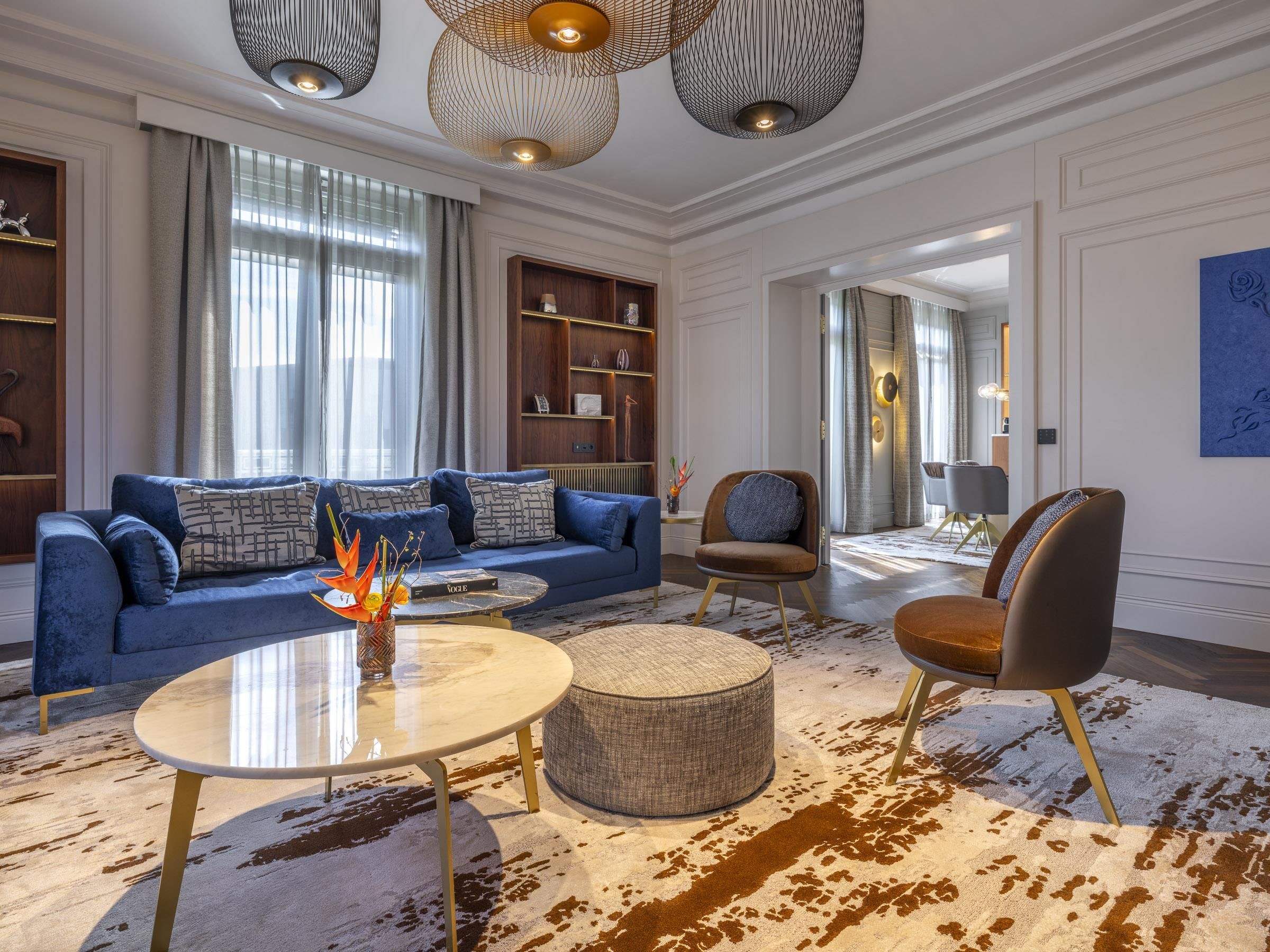 Ein modernes Wohnzimmer mit einem blauen Sofa, einem runden Couchtisch und einem gemusterten Teppich.