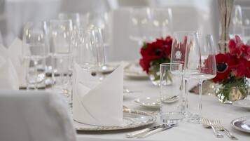 Ein Tisch ist für ein formelles Dinner gedeckt, mit klarem Glas, Besteck und einer weißen Tischdecke.
