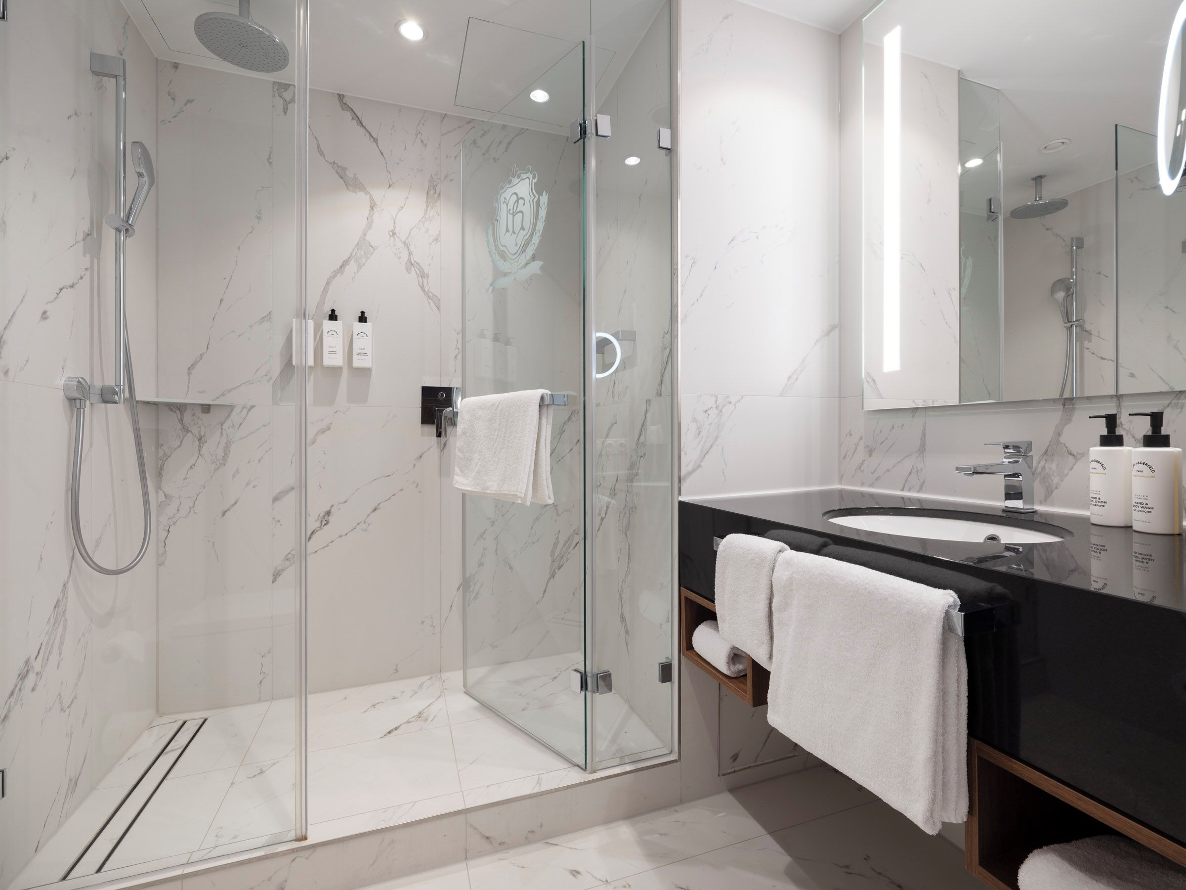 A modern bathroom with a glass-enclosed shower, a vanity with a black countertop, and a large mirror.