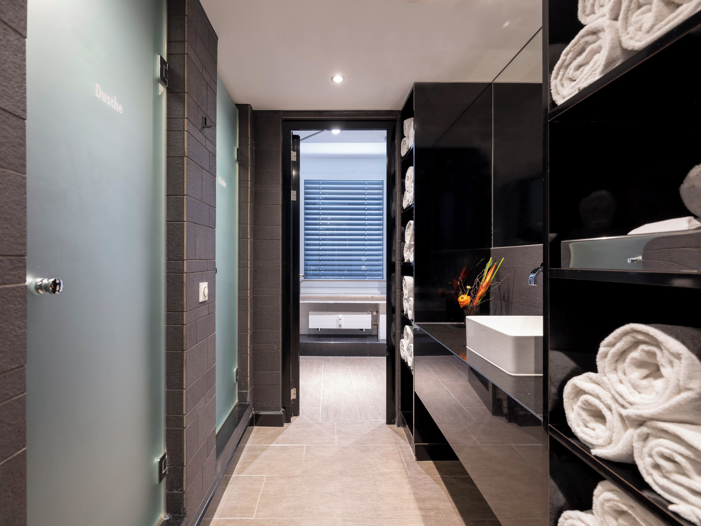 Une salle de bain moderne avec une porte en verre, un lavabo et des serviettes.