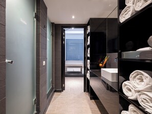 Une salle de bain moderne avec une porte en verre, un lavabo et des serviettes.