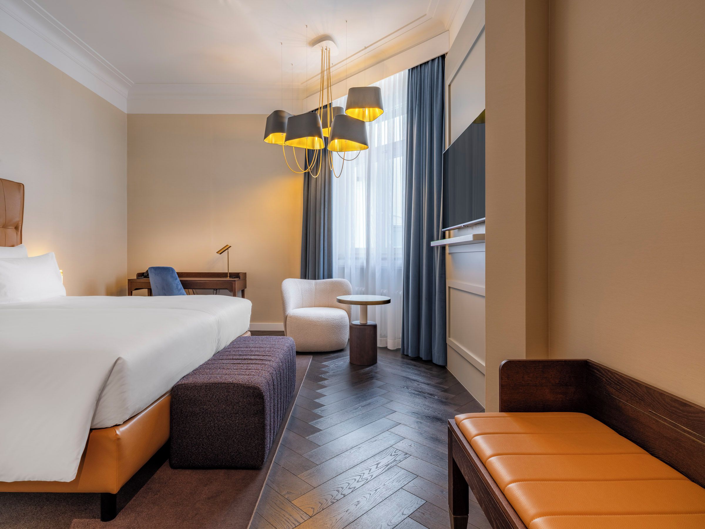 Una camera d'albergo con un letto grande, una sedia, un tavolino e una panca.