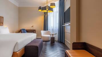 Una camera d'albergo con un letto grande, una sedia, un tavolino e una panca.