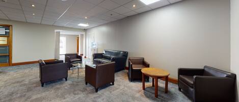 A conference room with a carpeted floor, a glass table, and several leather chairs.