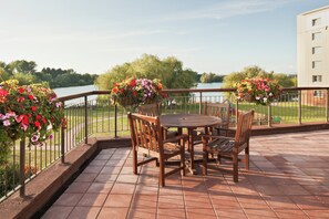 Una terraza con mesa y sillas, con vistas al agua y a la vegetación.