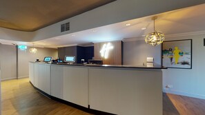 A modern reception desk with digital displays, a unique geometric light fixture, and a minimalist design.