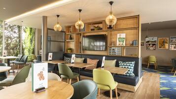 Enjoy a meal at this restaurant with a variety of seating options, including round tables, a communal table, and a sofa area.