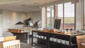 A breakfast bar with a menu board, coffee machine, and various breakfast items.
