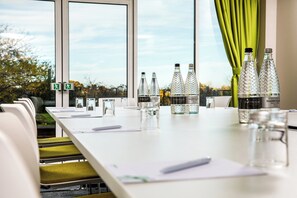 Un salón de conferencias con una larga mesa, sillas y botellas de agua Harrogate.