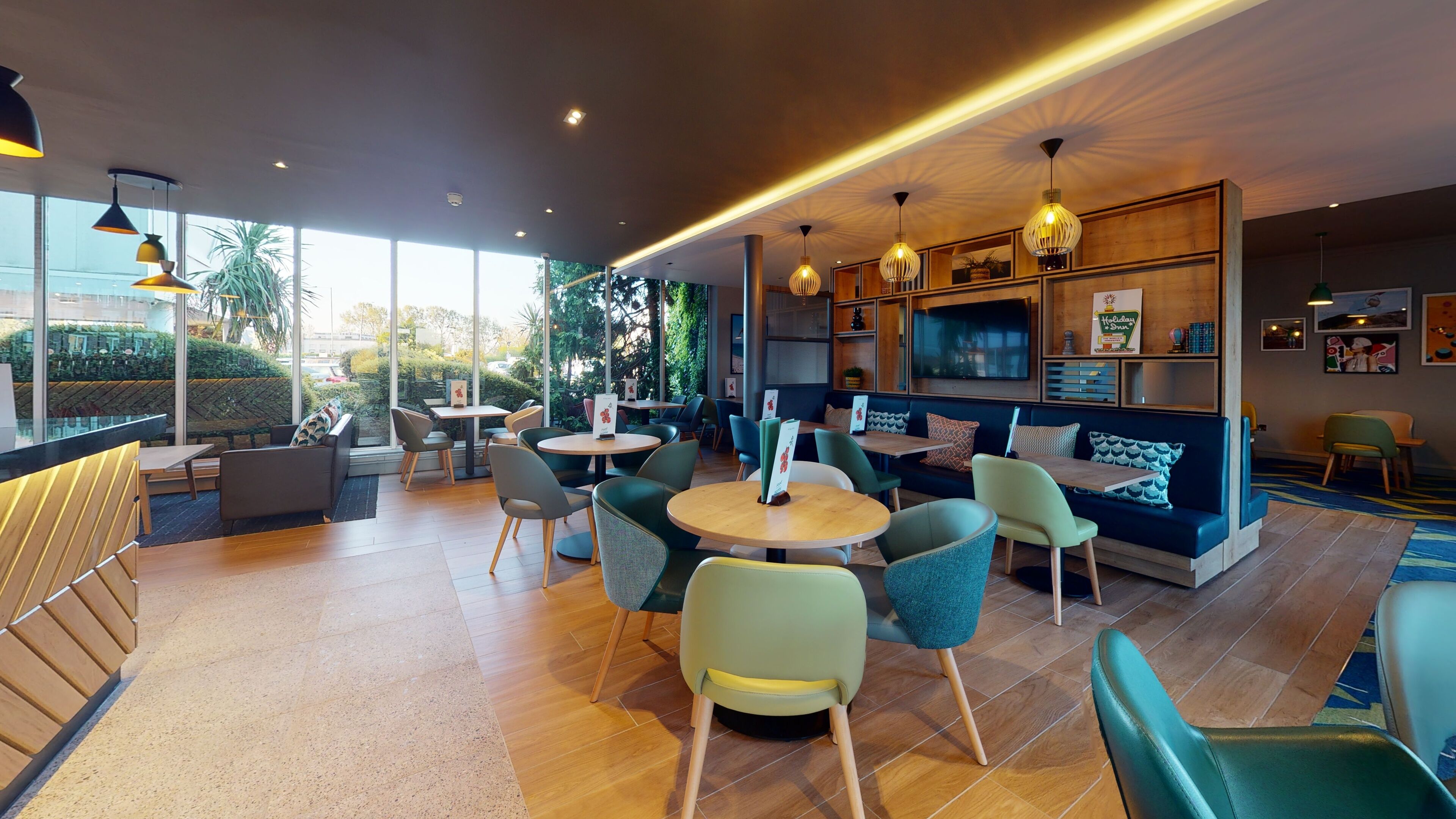 A modern cafe with round tables, comfortable seating, and a large window offering a view of the outdoors.