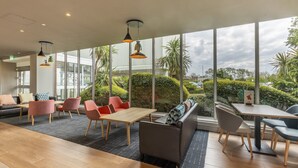 Un área de estar moderna con ventanas amplias, suelo de madera y muebles contemporáneos.