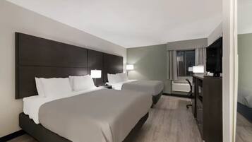 A hotel room with two beds, a desk, a chair, a television, and a window with curtains.