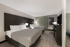 A hotel room with two beds, a desk, a chair, a television, and a window with curtains.
