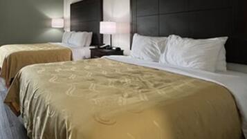 A hotel room with two beds, each with a headboard and bedside tables.