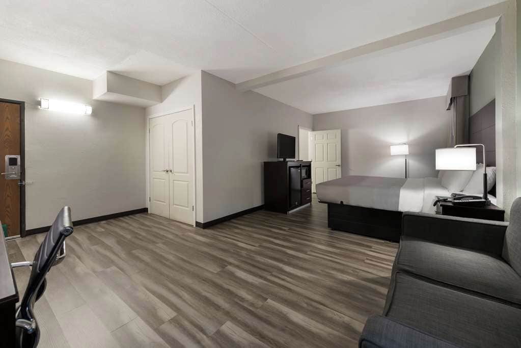 A modern hotel room with a flat-screen TV, a sofa, a desk, and a lamp.
