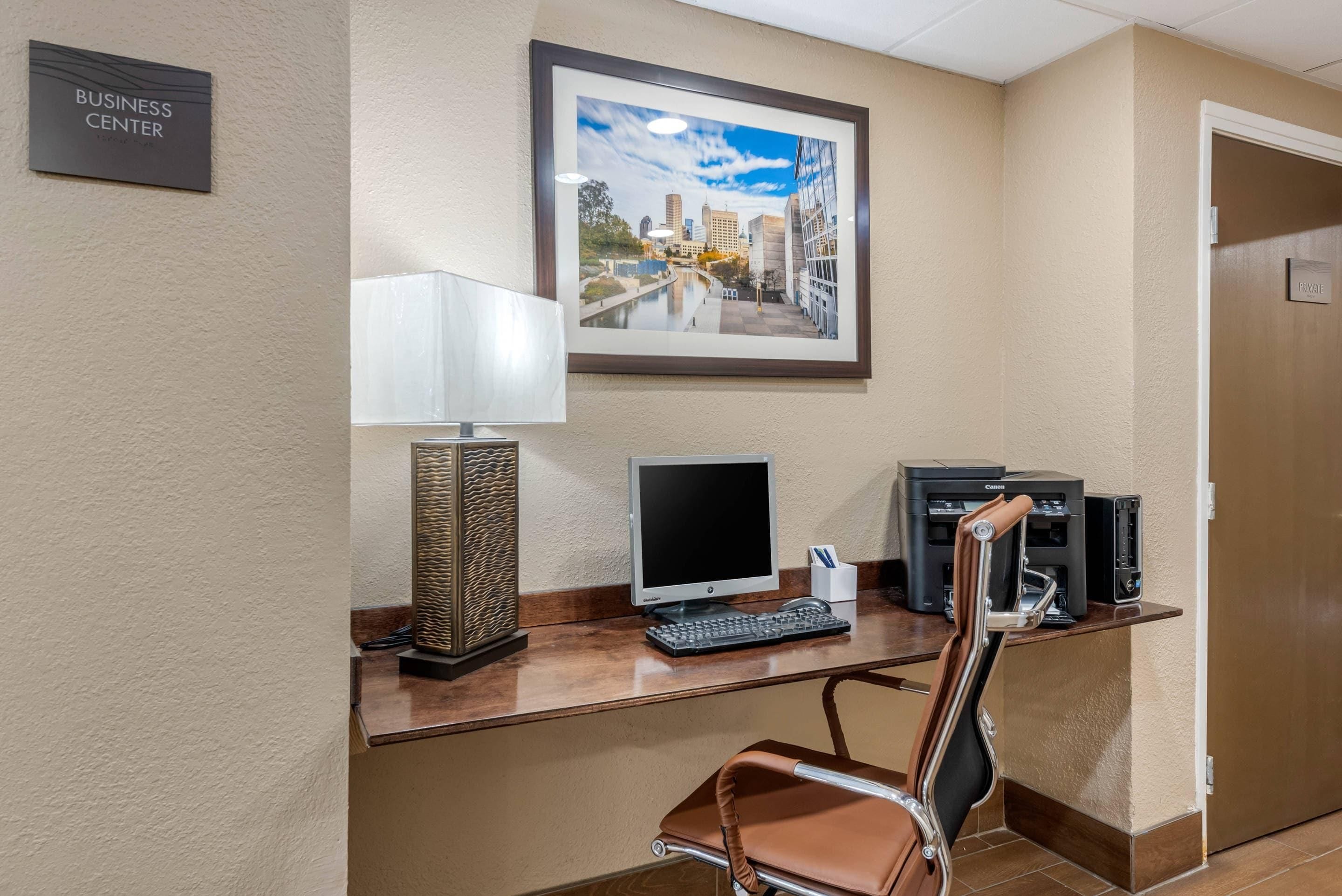 A business center desk with a computer, printer, and chair.
