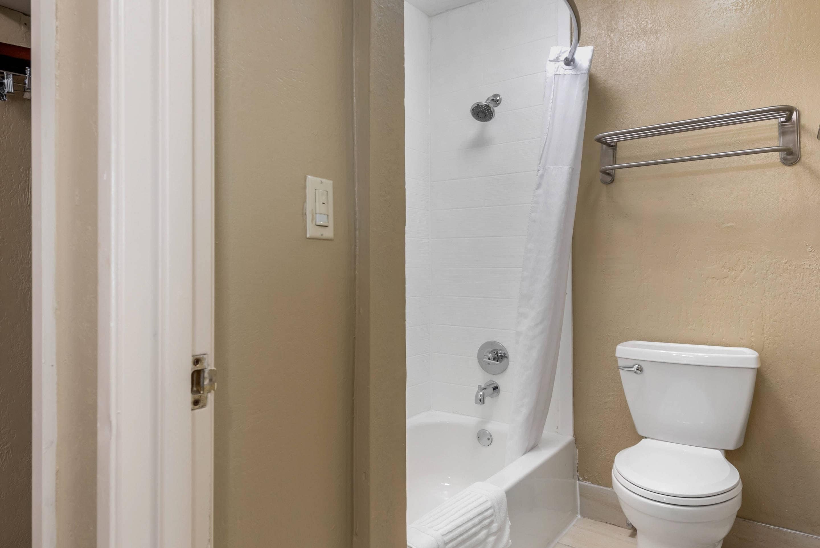 A bathroom with a bathtub, toilet, and a towel rack.