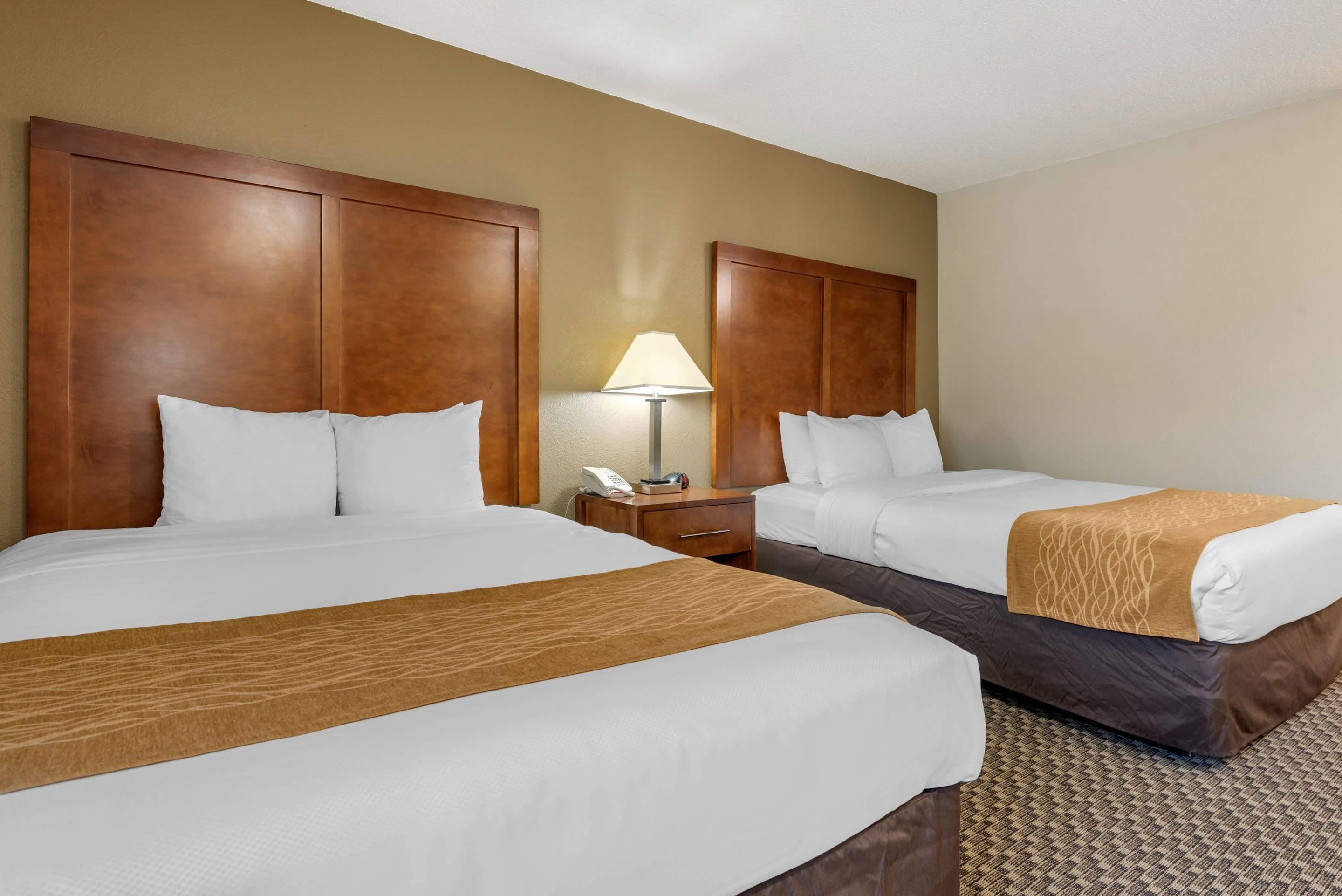 Une chambre d’hôtel avec deux lits, une table de chevet avec une lampe et un téléphone.