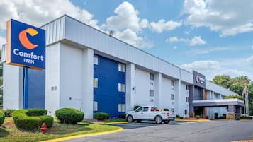 A Comfort Inn hotel with a large blue entrance, a white exterior, and a parking lot with a white truck.