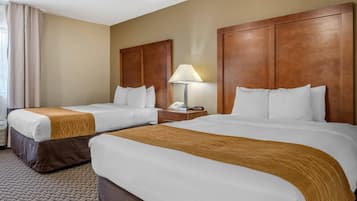 A hotel room with two beds, a nightstand with a lamp, and a telephone.