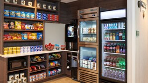 A snack and beverage vending area with various snack options and a refrigerated section. - DoubleTree by Hilton Raleigh Crabtree Valley (Raleigh)