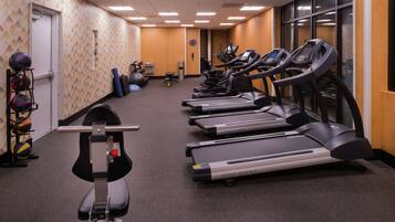 A gym with treadmills, a rowing machine, and exercise balls.