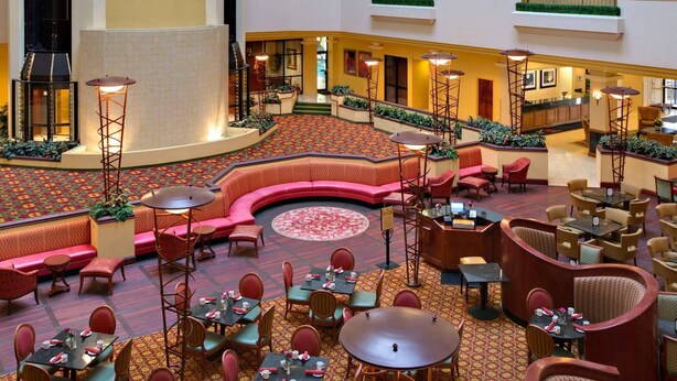 A hotel lobby with a central seating area, multiple dining tables, and a decorative floor pattern. - Radisson Hotel Cedar Rapids (Cedar Rapids)