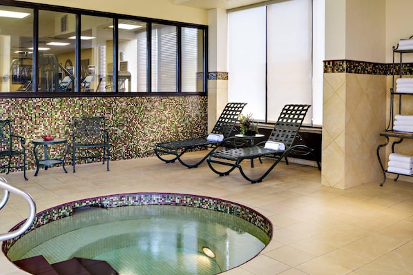 A spa area with a hot tub, lounge chairs, and exercise equipment.