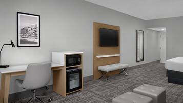 A hotel room with a desk, microwave, oven, bench, ottoman, bed, TV, and a framed picture on the wall.