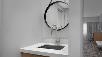 Un baño moderno con un lavamanos blanco, un espejo grande y un mueble de madera.