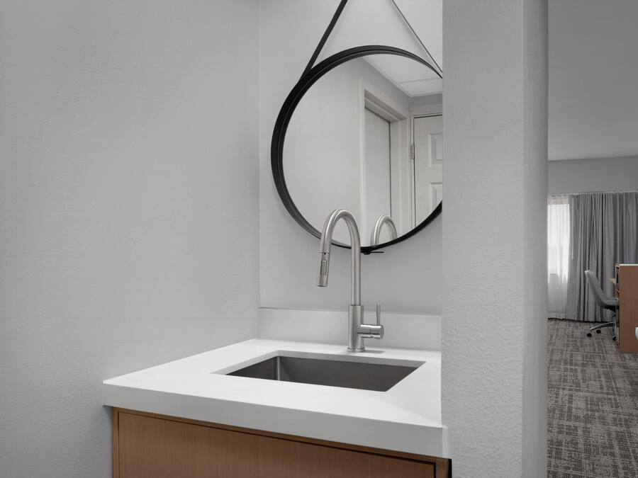 Un baño moderno con un lavamanos blanco, un espejo grande y un mueble de madera.