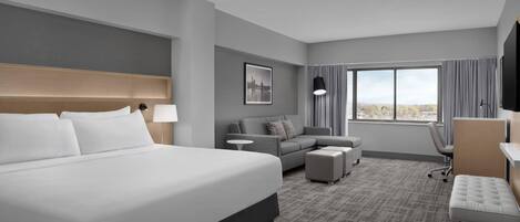 Een hotelkamer met een groot bed, een bank, een bureau en een televisie.