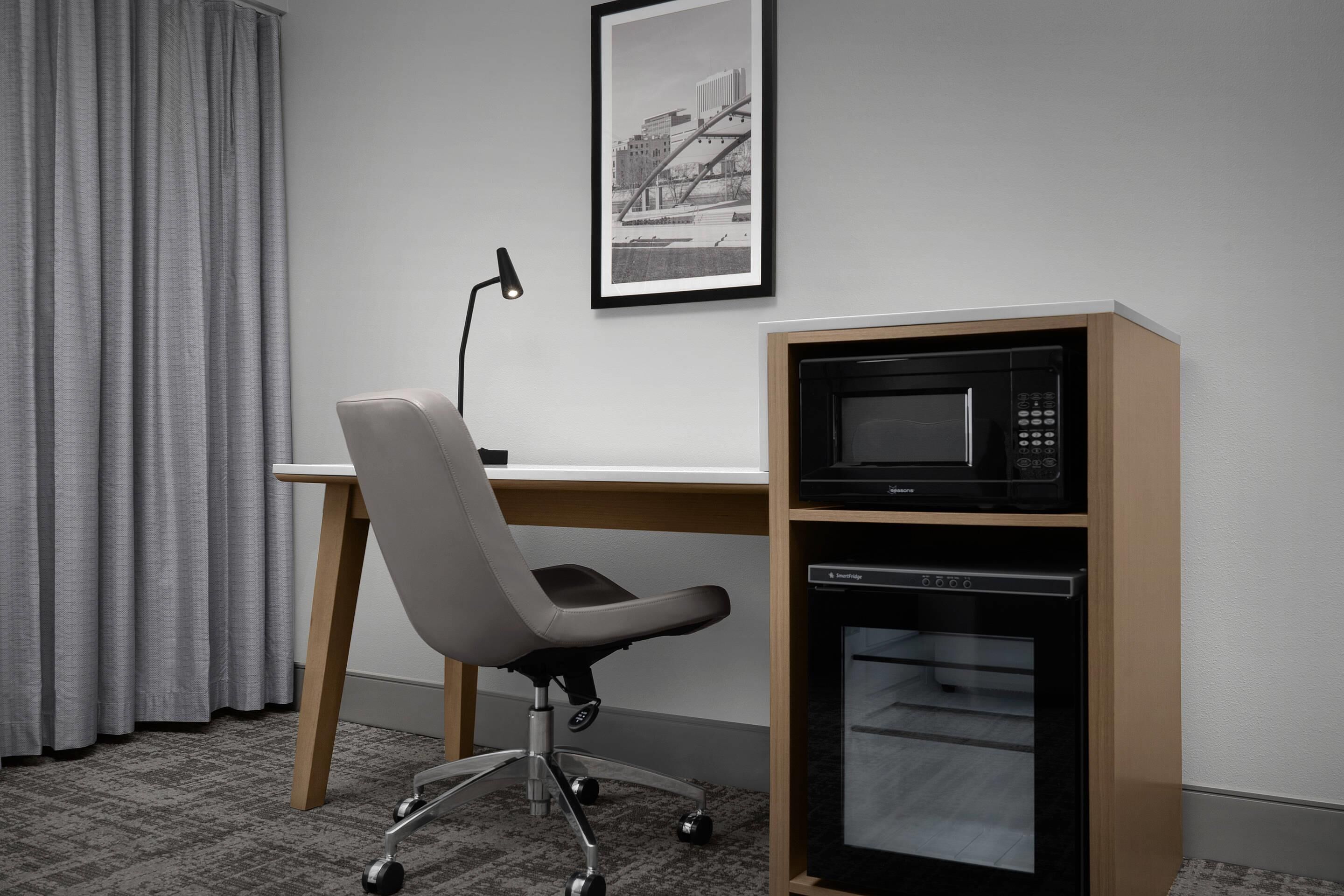 Ein Zimmer mit Schreibtisch, Bürostuhl, Mikrowelle und Geschirrspüler.