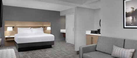 A hotel room with a bed, a sofa, a desk, and a TV.