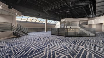 A spacious indoor area with a patterned carpet, multiple staircases, and a glass partition.