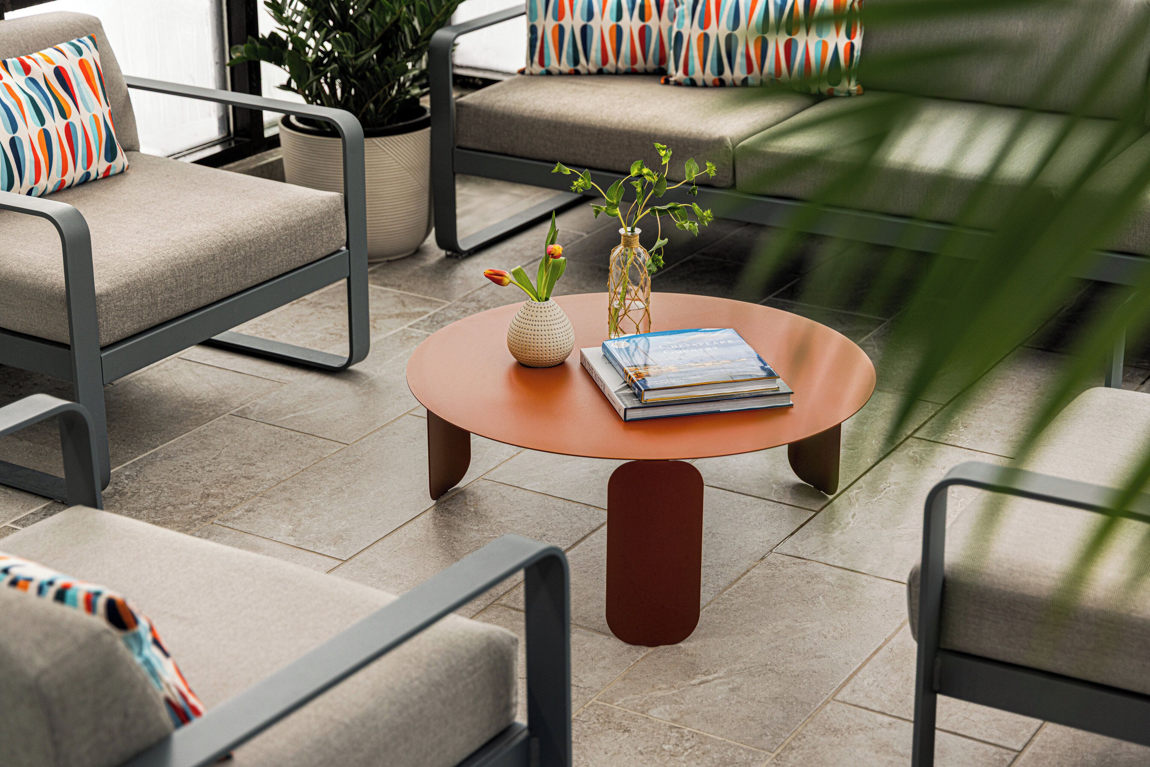 A modern outdoor seating area with a round table, chairs, and a potted plant.