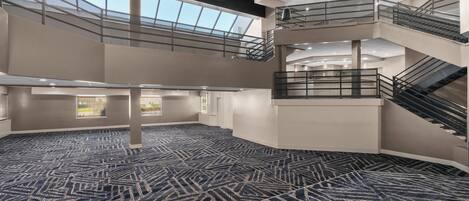 A spacious atrium with a high ceiling, multiple staircases, and a patterned carpet.