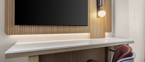 Una habitación moderna con un televisor de pantalla plana grande montado en una pared de paneles de madera, una consola blanca y un sillón de cuero marrón.