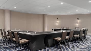 Una sala de conferencias con una gran mesa, sillas y piso alfombrado.