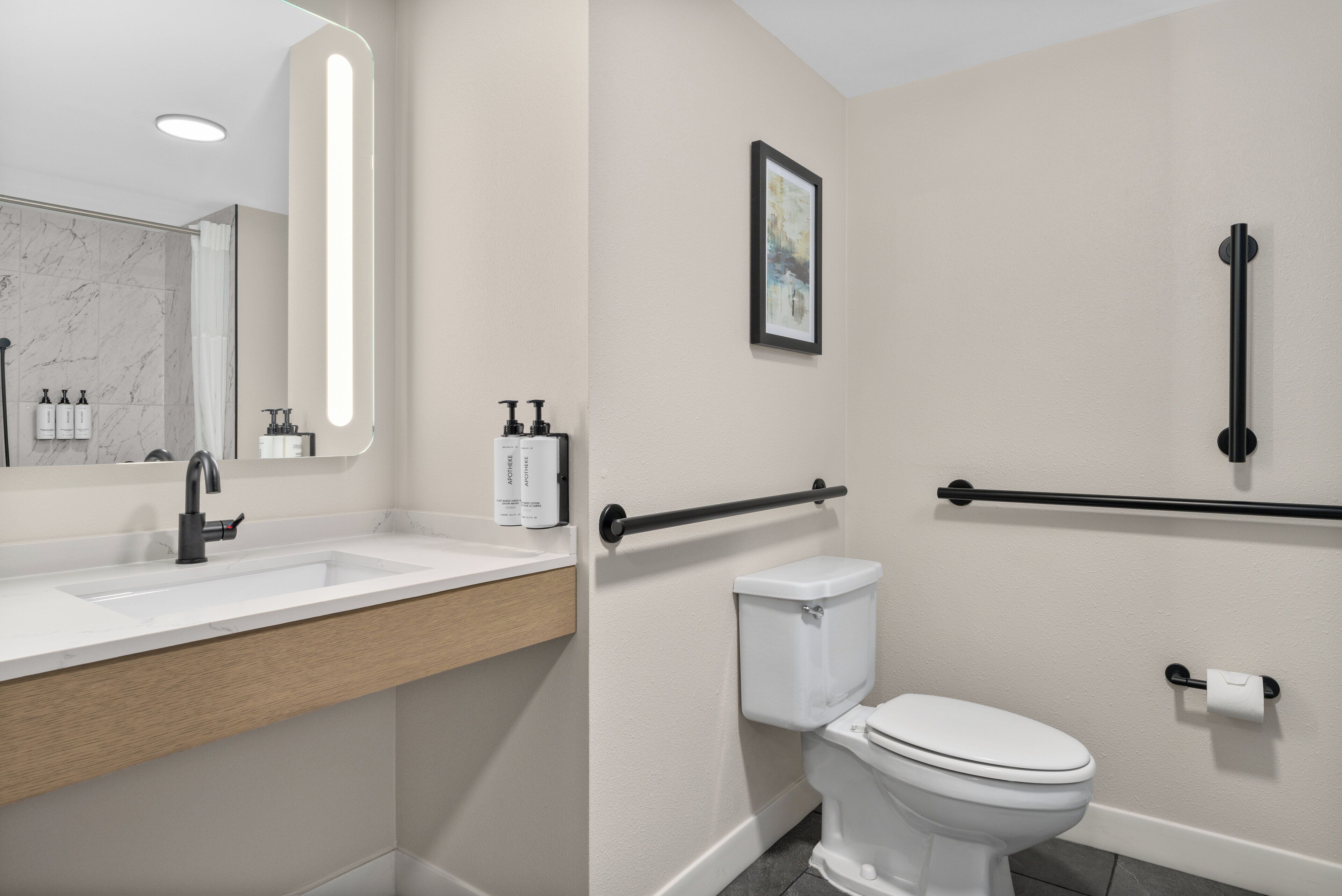A modern bathroom with a white sink, mirror, and toilet.
