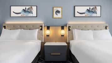 A hotel room with two beds, a nightstand, and wall-mounted artwork.