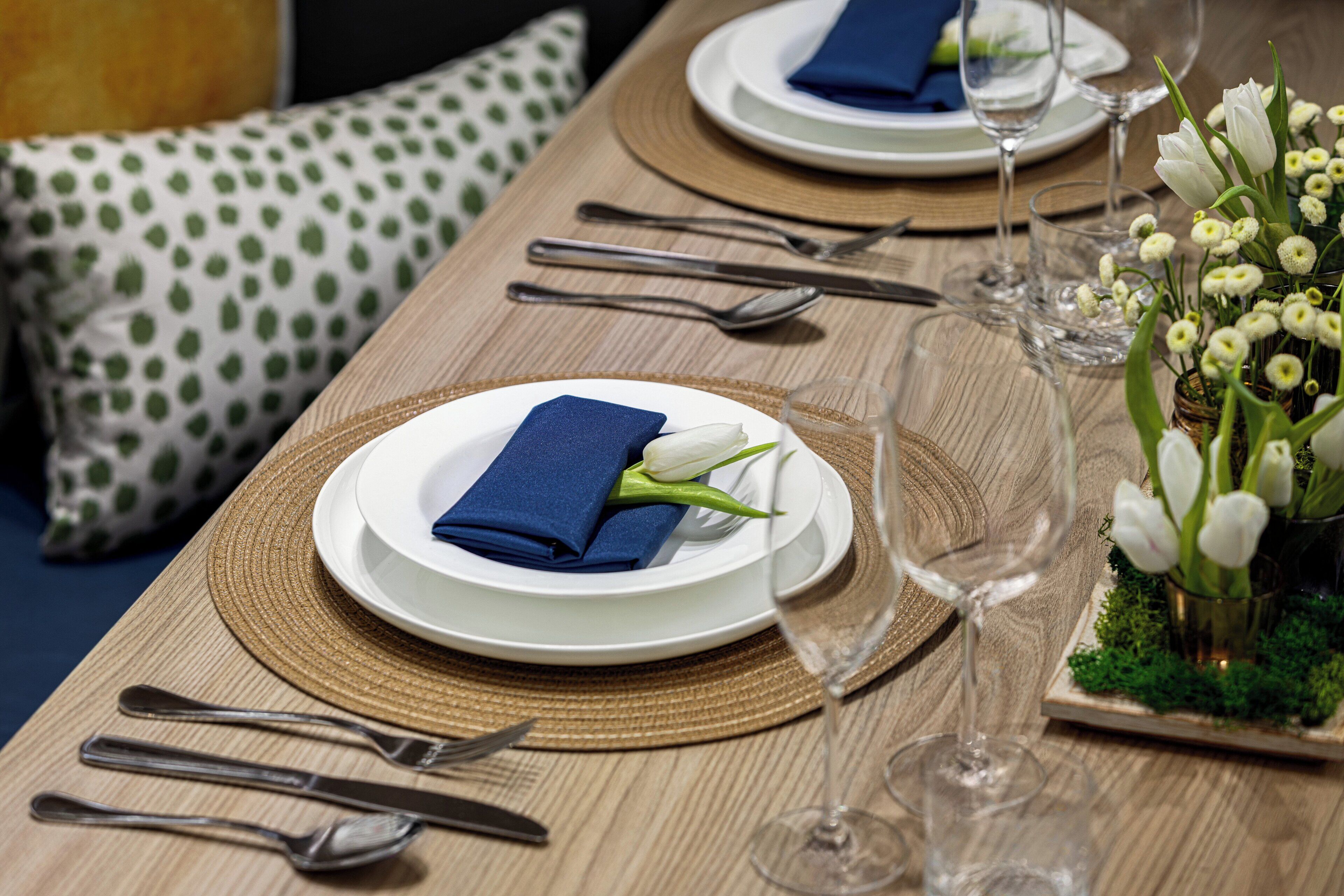 A neatly set dining table with plates, cutlery, and a folded napkin.