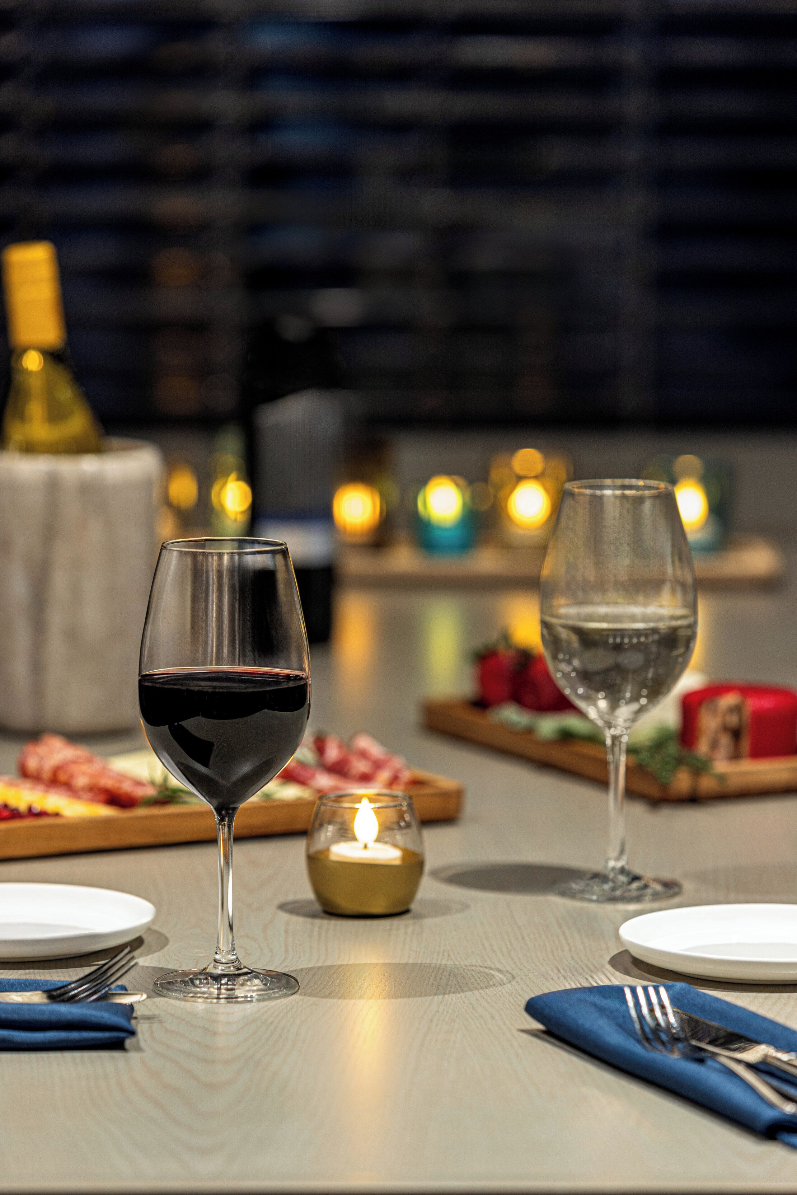 A table set for dining with two wine glasses, a candle, and a small decorative item.